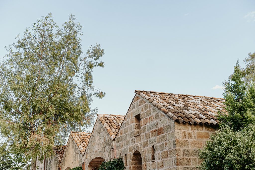 I tetti in coppi e i muri in pietra dei corpi di fabbrica della casina, fra gli eucalipti